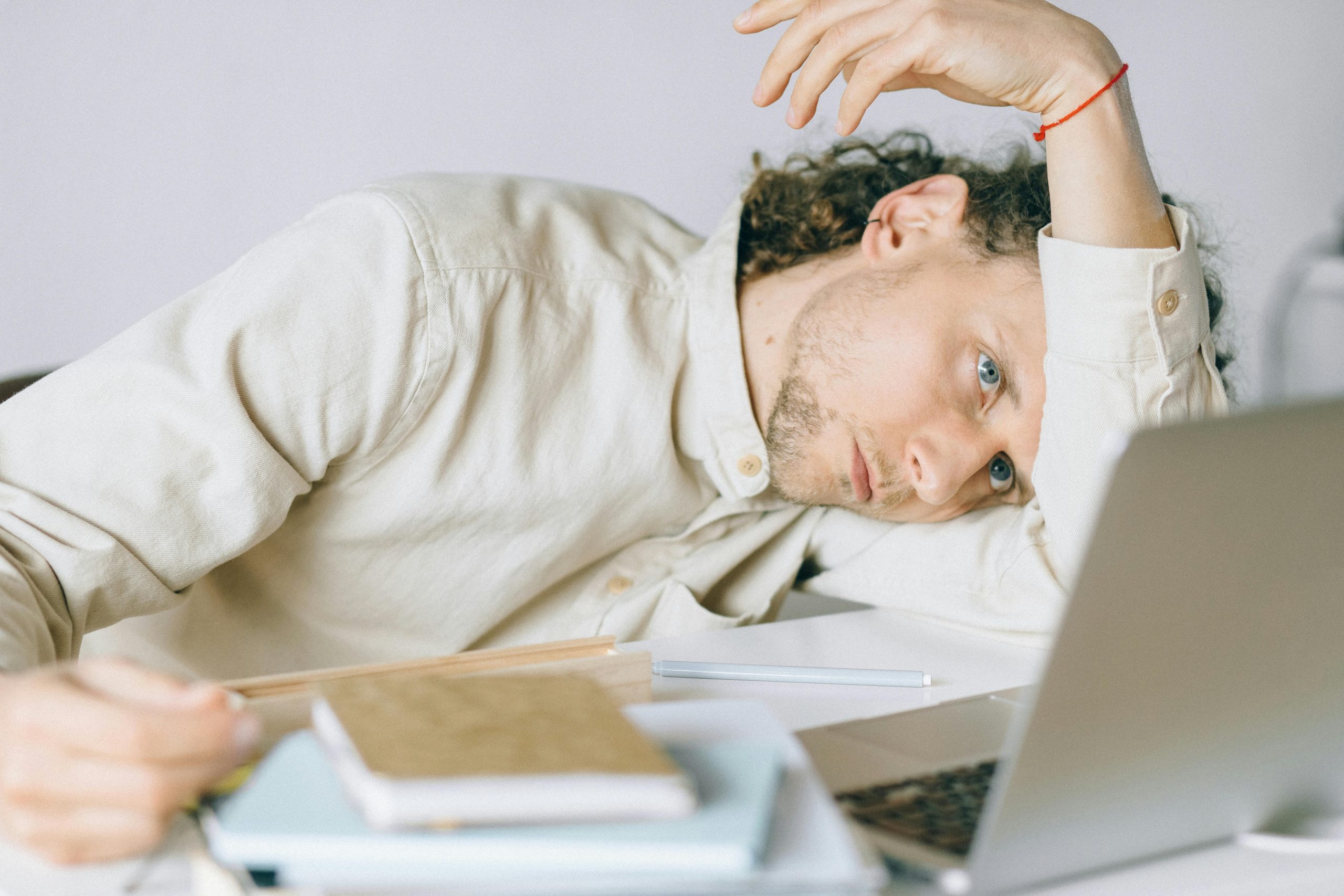 An employee working from home burnt out from spending too much time working, laying his head on the desk.